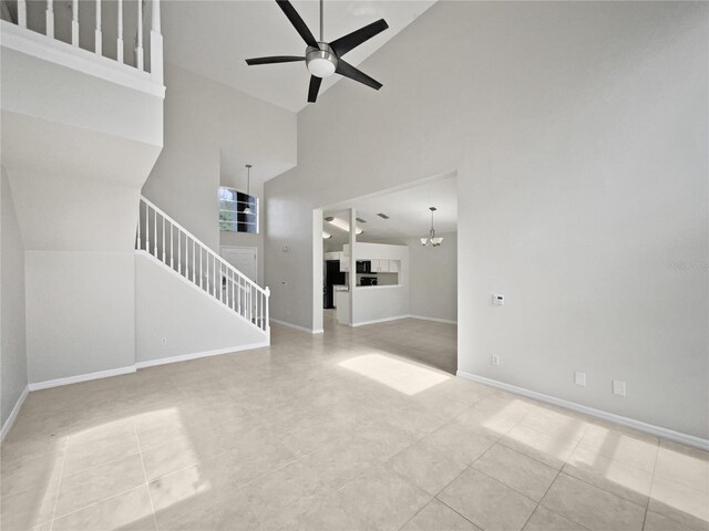 unfurnished living room featuring light tile patterned floors, ceiling fan with notable chandelier, and high vaulted ceiling