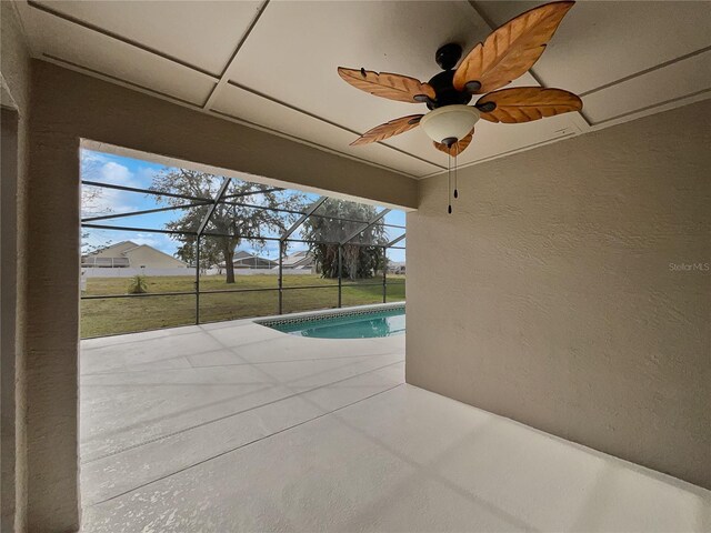 view of swimming pool featuring a lawn, glass enclosure, ceiling fan, and a patio area