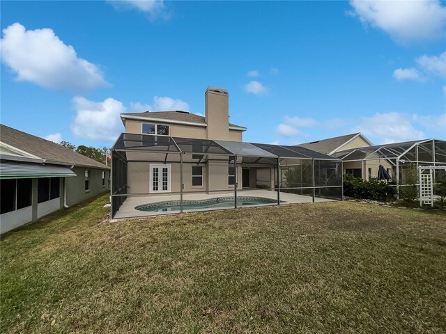 rear view of house featuring a lawn, glass enclosure, and a patio area