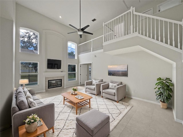 living room with a high ceiling, ceiling fan, and a tiled fireplace