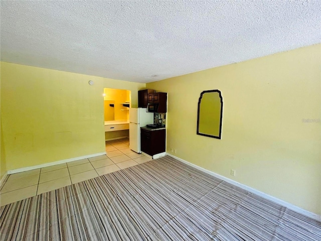 empty room with light tile patterned floors and a textured ceiling