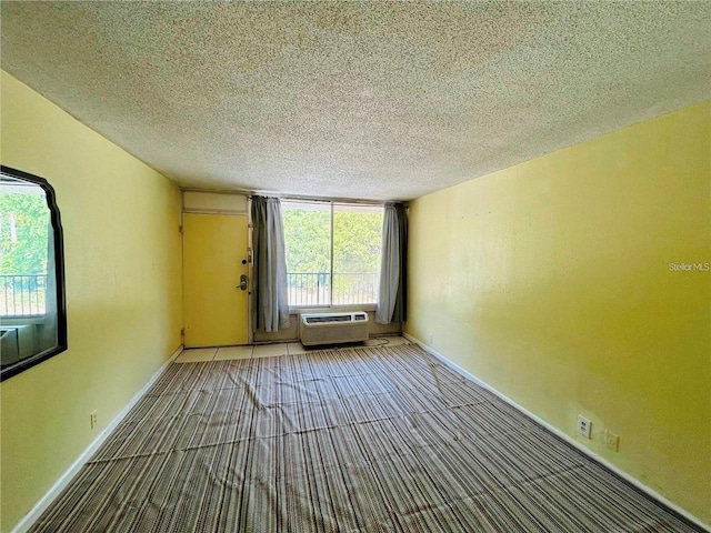 empty room featuring a wall mounted AC and a textured ceiling