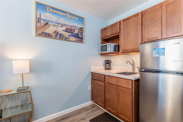 kitchen featuring sink, stainless steel refrigerator, and light hardwood / wood-style flooring