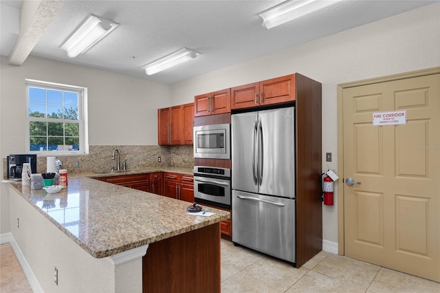 kitchen with light stone counters, light tile patterned floors, stainless steel appliances, and kitchen peninsula