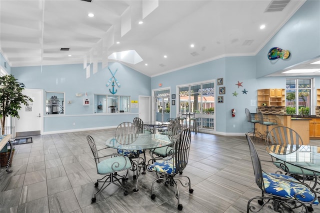 dining space with ornamental molding, a skylight, and high vaulted ceiling