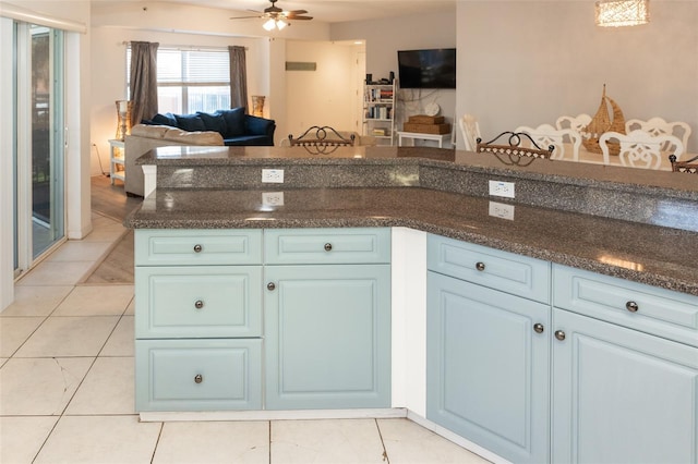 kitchen with light tile patterned floors, dark stone counters, and ceiling fan