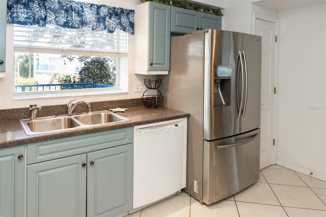 kitchen featuring stainless steel refrigerator with ice dispenser, dishwasher, sink, and light tile patterned floors