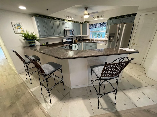 kitchen with sink, a breakfast bar area, kitchen peninsula, ceiling fan, and stainless steel appliances