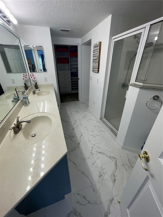 bathroom featuring vanity, an enclosed shower, and a textured ceiling