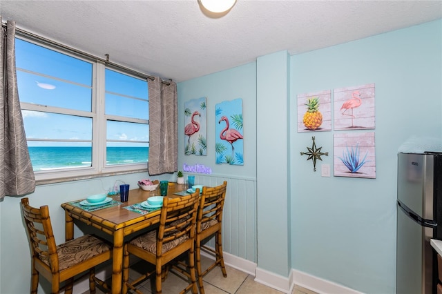 800 N Atlantic Ave Unit 301, Daytona Beach, FL 32118 - dining room with a textured ceiling, light tile patterned floors, a water view, and a wainscoted wall