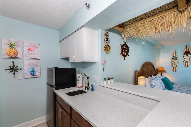 800 N Atlantic Ave Unit 301, Daytona Beach, FL 32118 - kitchen featuring a sink, freestanding refrigerator, white cabinetry, baseboards, and light stone counters