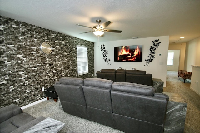 carpeted living room with a textured ceiling, a wealth of natural light, and ceiling fan