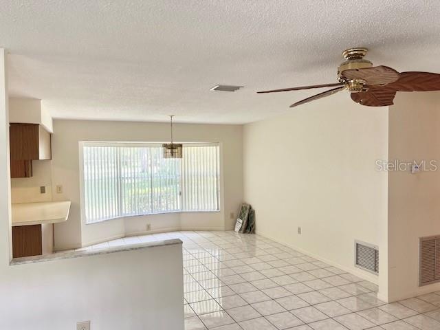 kitchen featuring ceiling fan, light tile patterned floors, pendant lighting, and a textured ceiling