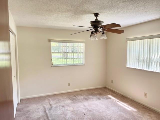 carpeted empty room with ceiling fan and a textured ceiling