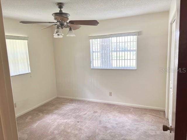 carpeted empty room featuring ceiling fan and a textured ceiling