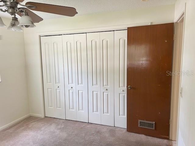 unfurnished bedroom with ceiling fan, a closet, and carpet