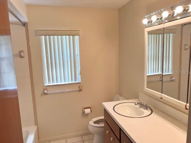 full bathroom featuring tile patterned floors, toilet, tiled shower / bath, and vanity