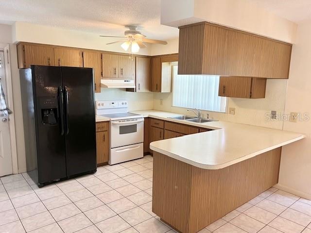 kitchen featuring black refrigerator with ice dispenser, sink, white range with electric stovetop, light tile patterned floors, and kitchen peninsula