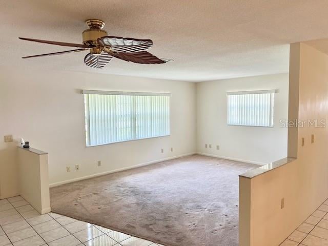 spare room featuring ceiling fan, a healthy amount of sunlight, and light tile patterned floors