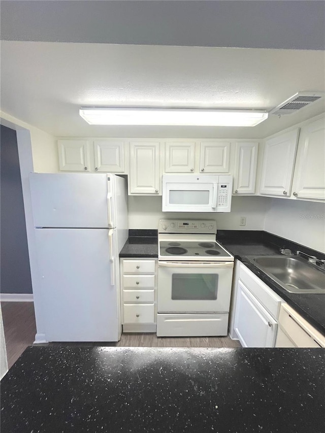 kitchen with sink, white cabinets, wood-type flooring, and white appliances