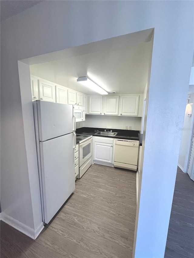 kitchen with dark hardwood / wood-style flooring, white appliances, white cabinetry, and sink