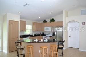 kitchen with stainless steel fridge, a kitchen island, and a kitchen breakfast bar