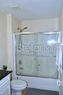 full bathroom with shower / bath combination with glass door, vanity, and toilet