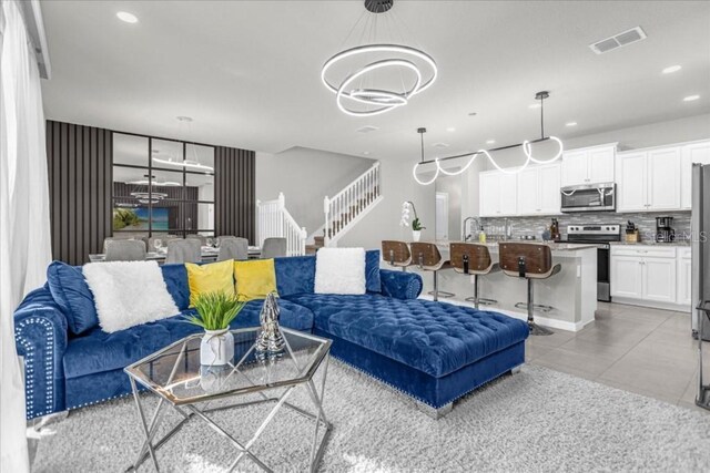 living area featuring a notable chandelier, light tile patterned floors, recessed lighting, visible vents, and stairway