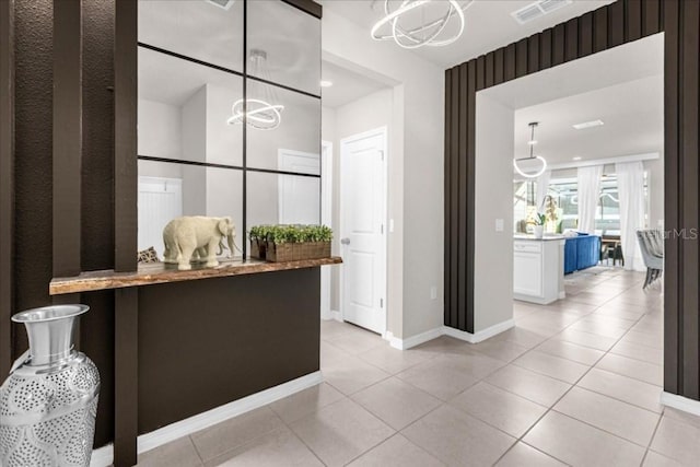 interior space with a notable chandelier, visible vents, hanging light fixtures, light tile patterned flooring, and baseboards