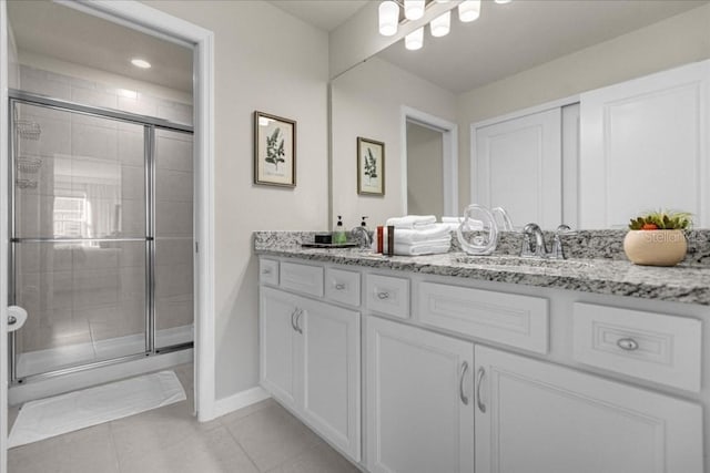 bathroom featuring tile patterned flooring, baseboards, a shower stall, and vanity