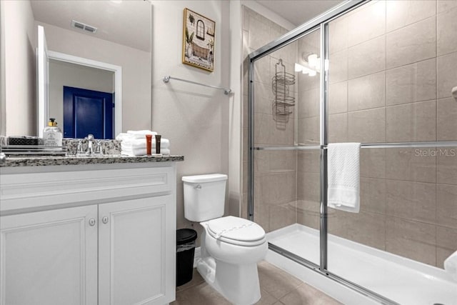 bathroom featuring toilet, visible vents, vanity, a shower stall, and tile patterned floors