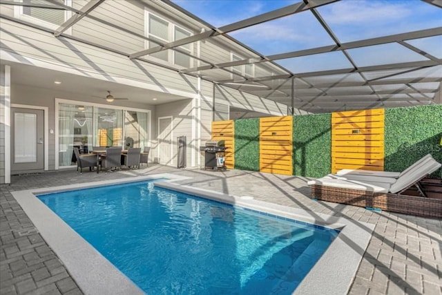 pool featuring a patio area, ceiling fan, glass enclosure, and grilling area