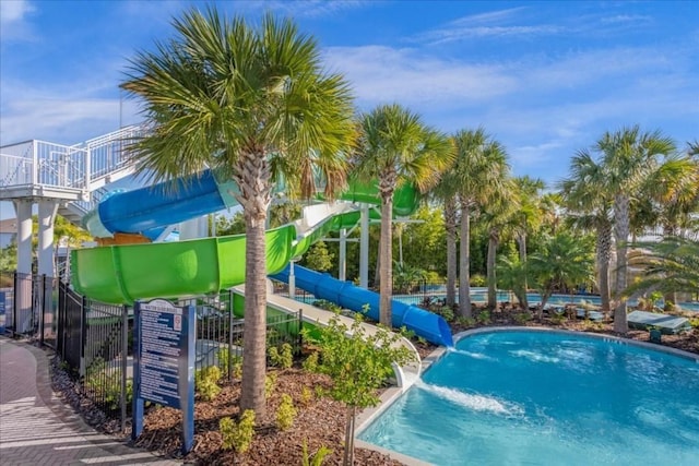 community pool with a water slide and fence