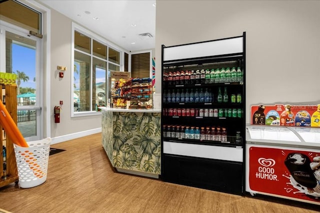 bar with a bar, visible vents, baseboards, and wood finished floors