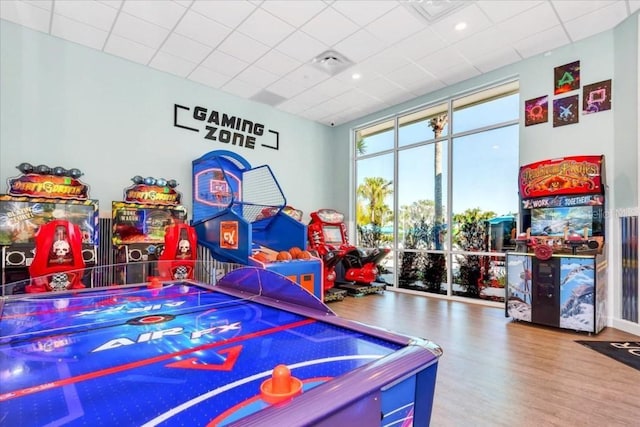 game room featuring a wall of windows, hardwood / wood-style flooring, and a paneled ceiling