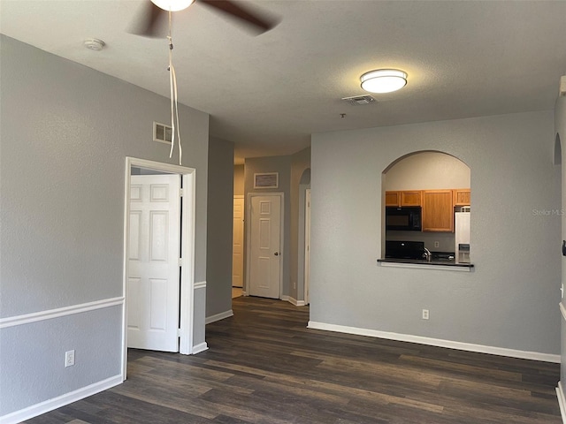 empty room with ceiling fan and dark wood-type flooring