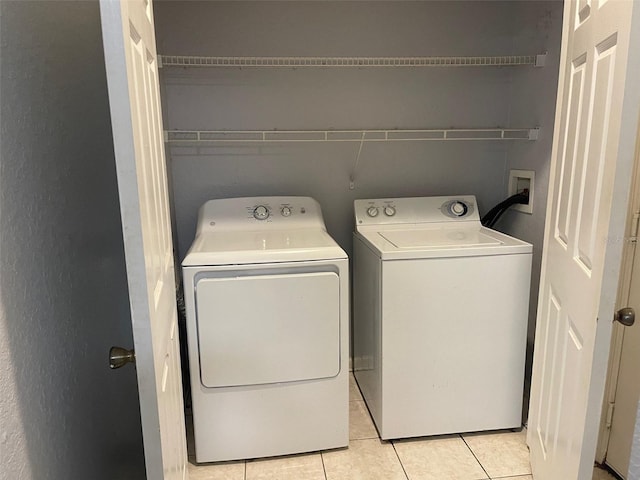 clothes washing area with washing machine and dryer and light tile patterned floors