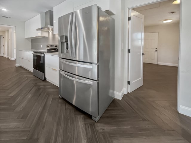 kitchen featuring dark parquet flooring, stainless steel appliances, white cabinetry, and wall chimney range hood