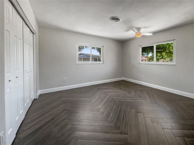 unfurnished bedroom featuring multiple windows, ceiling fan, and dark parquet floors