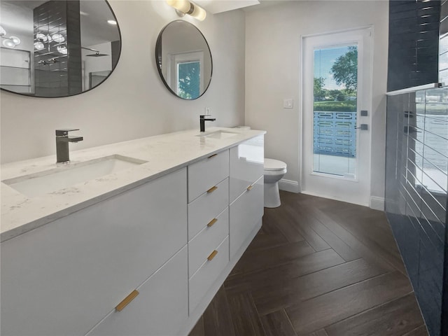 bathroom featuring vanity, toilet, parquet flooring, and walk in shower