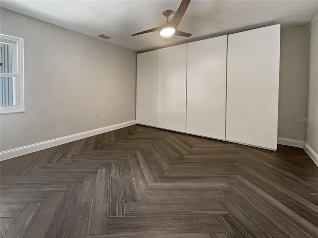 unfurnished bedroom with dark parquet flooring, ceiling fan, and a closet