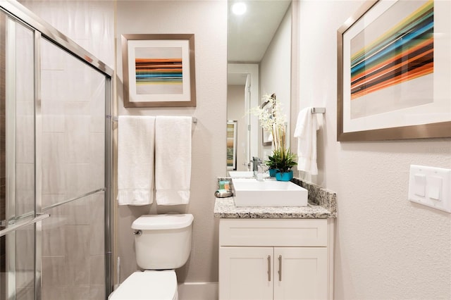 bathroom with vanity, a shower with door, and toilet