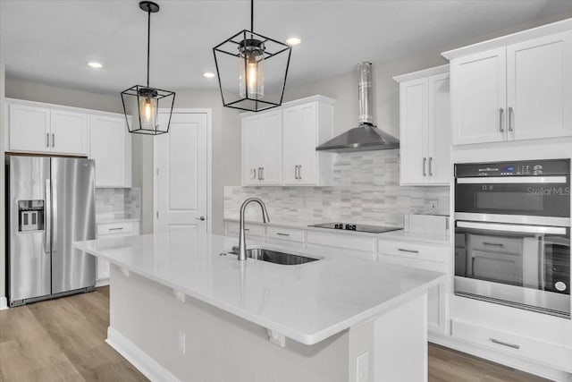 kitchen with decorative light fixtures, stainless steel appliances, wall chimney exhaust hood, and white cabinetry