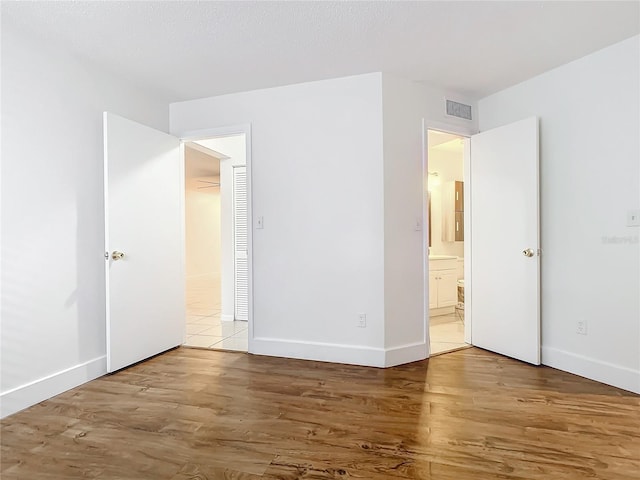 unfurnished bedroom featuring light hardwood / wood-style floors and ensuite bathroom