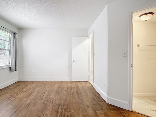 empty room with light wood-type flooring and a textured ceiling