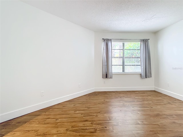 empty room with a textured ceiling and hardwood / wood-style flooring