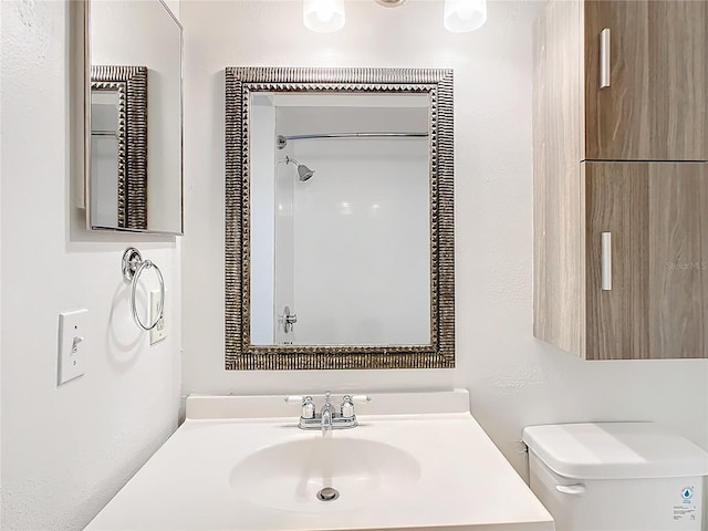 bathroom with toilet, vanity, and walk in shower