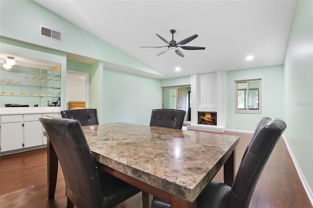 dining room with a fireplace, lofted ceiling, ceiling fan, and dark hardwood / wood-style floors