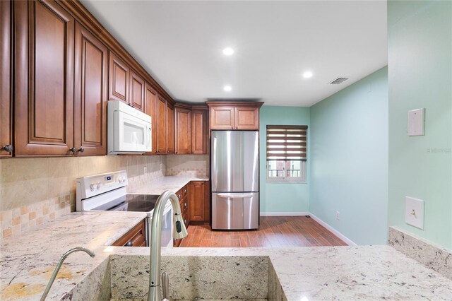8 Escondido Cir Unit 78, Altamonte Springs, FL 32701 - kitchen with white appliances, light wood finished floors, backsplash, recessed lighting, and brown cabinetry