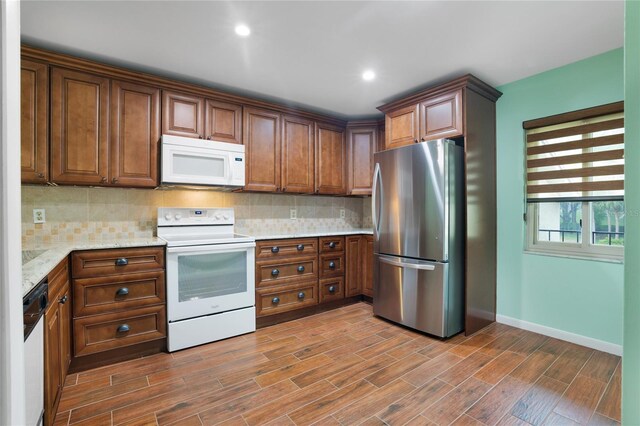 8 Escondido Cir Unit 78, Altamonte Springs, FL 32701 - kitchen with white appliances, backsplash, baseboards, light stone countertops, and recessed lighting
